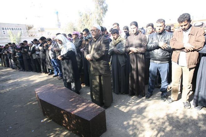 Mourners pray next to the coffin of a victim who, according to relatives, was killed in artillery fire by the Iraqi army in the city of Falluja